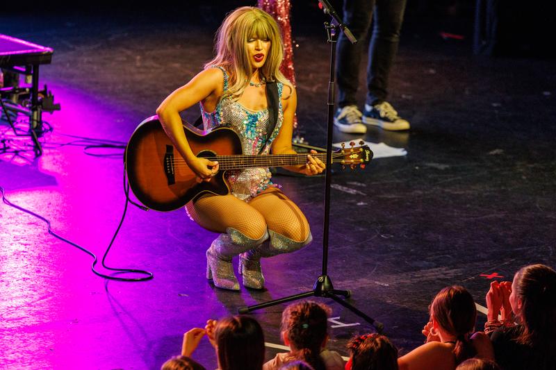Playing guitar at the front of the stage, close to the audience